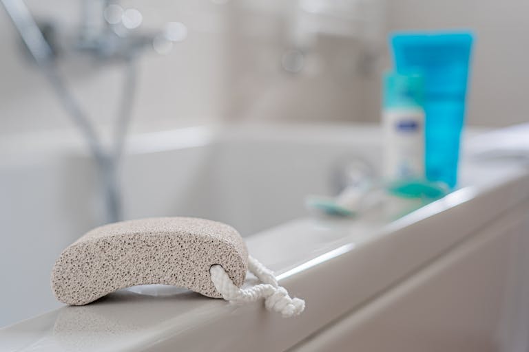 A pumice stone placed on a bathtub edge, ideal for exfoliating in a contemporary bathroom setting.
