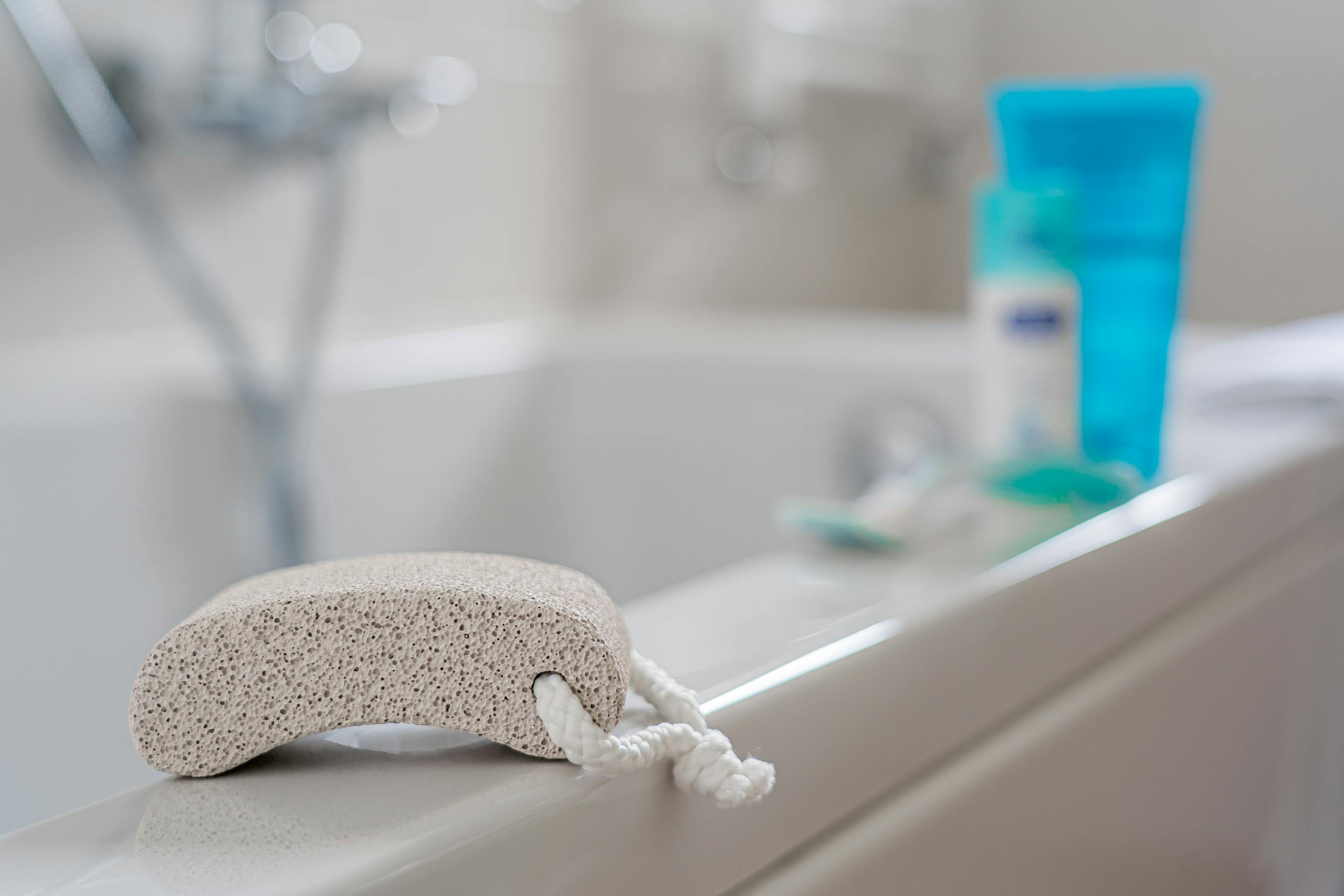 A pumice stone placed on a bathtub edge, ideal for exfoliating in a contemporary bathroom setting.