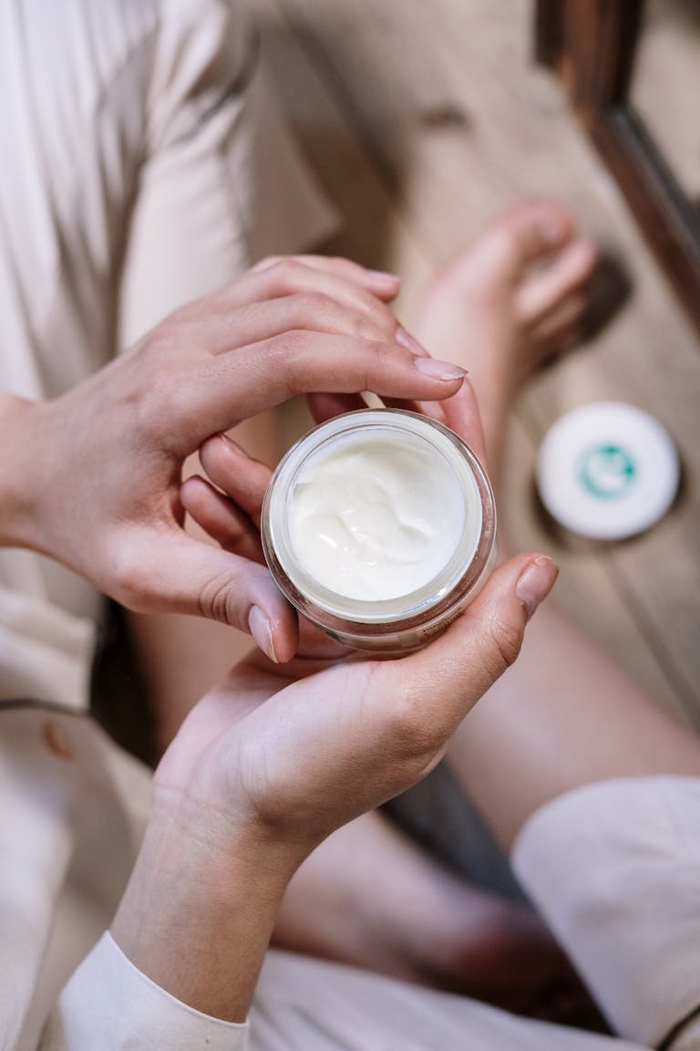 Close-up of woman's hands applying skincare cream during morning routine indoors.