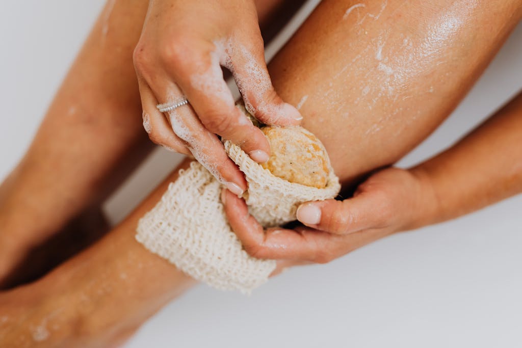 Detailed view of a person exfoliating their leg with a natural loofah sponge for skin care.