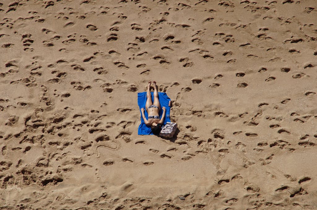 A woman in a bikini sunbathes on a sandy beach in Mazatl&aacute;n, Mexico, surrounded by footprints.