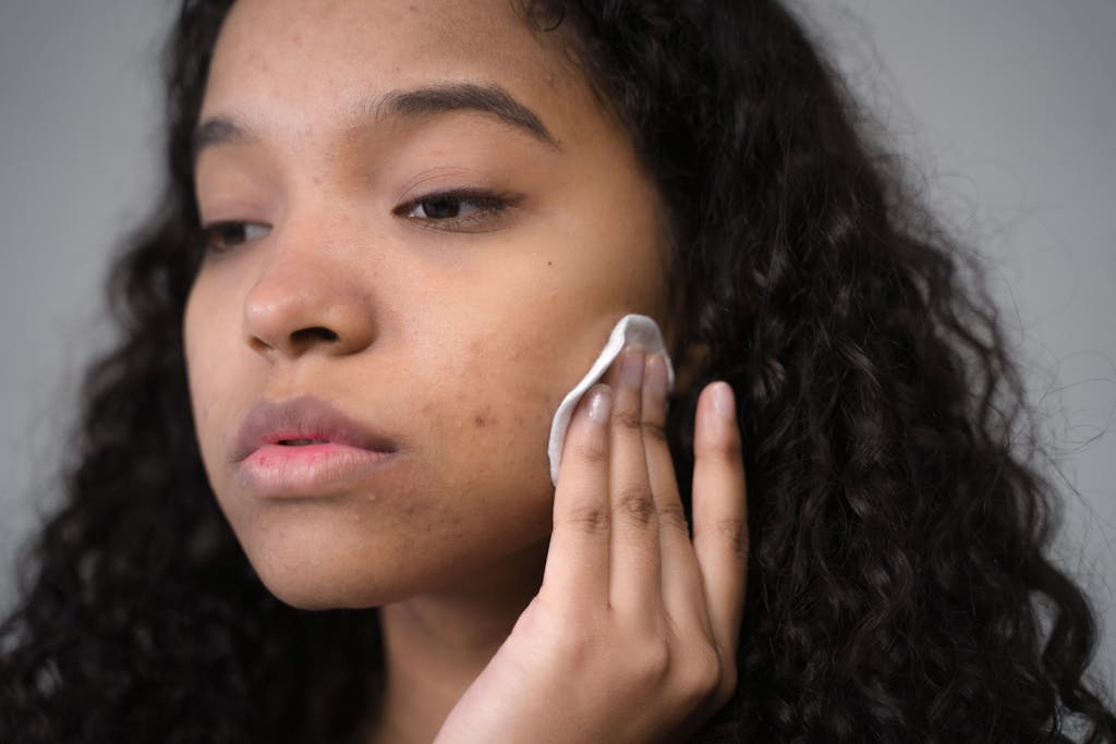 Close-up of a black woman gently removing his makeup before a tanning bed session, focusing on clear and healthy skin.